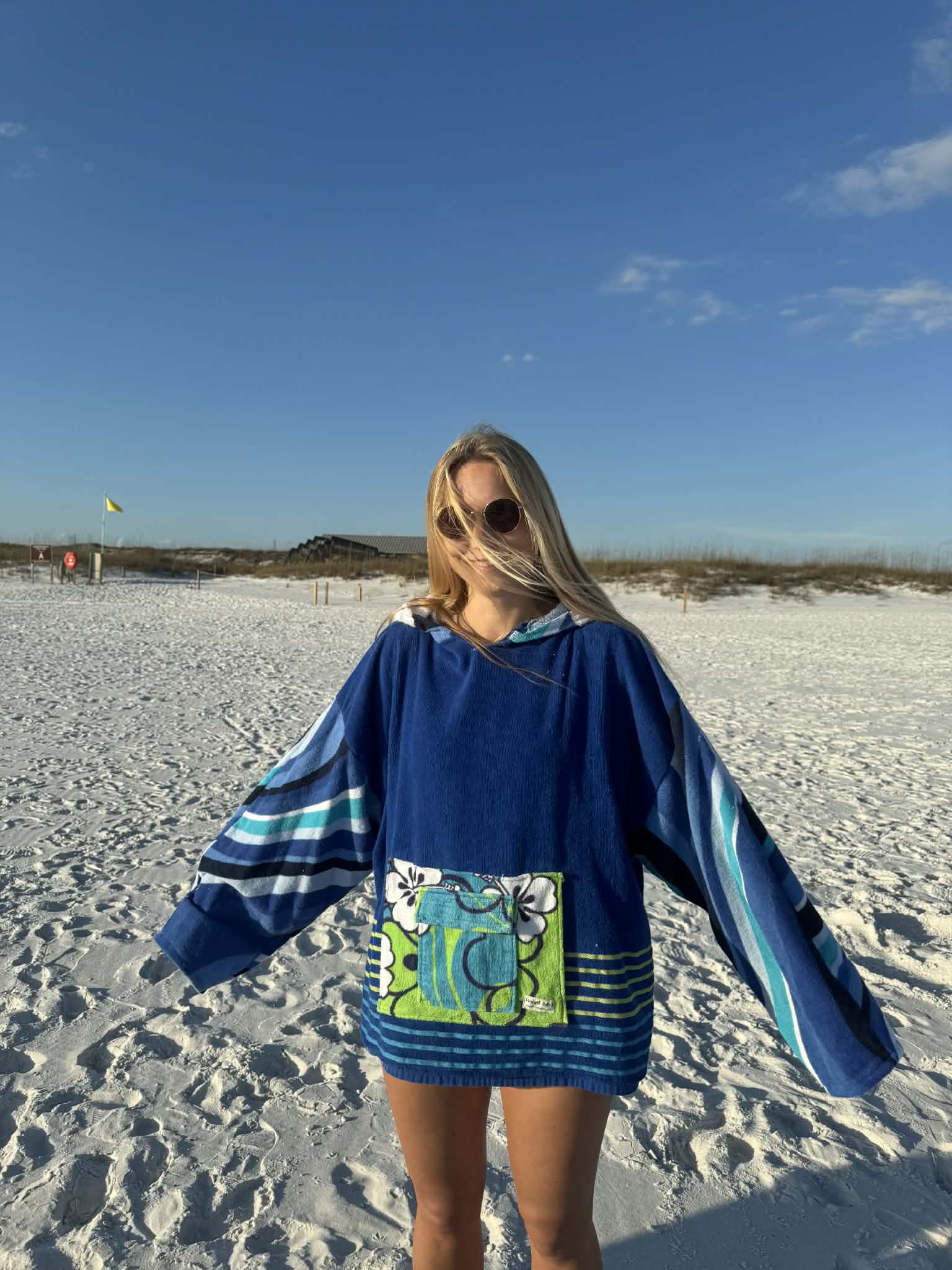 Person wearing a blue dress with a green design on a sandy beach